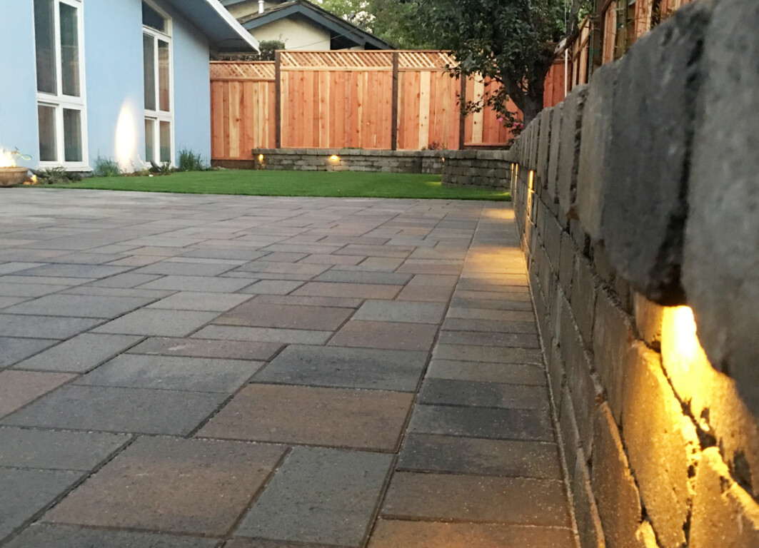 Professional concrete patio installation with retaining wall and lighting